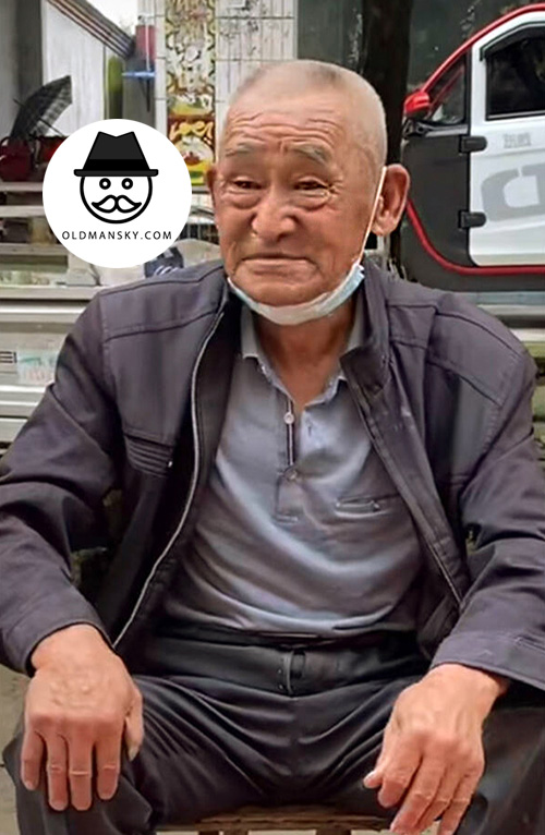 Old man in black jacket sold vegetables by the roadside