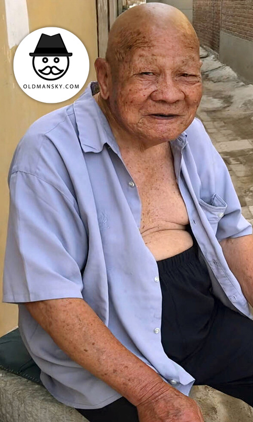 bald head old man in blue shirt and black trousers at home