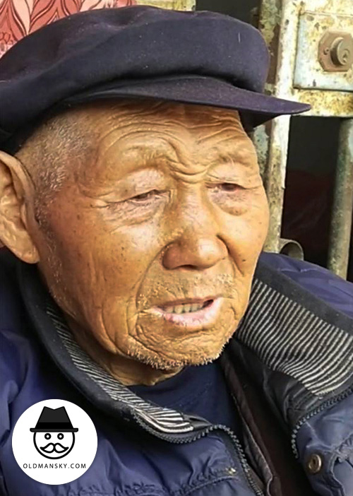 Old man wore a brown hat and coat at home