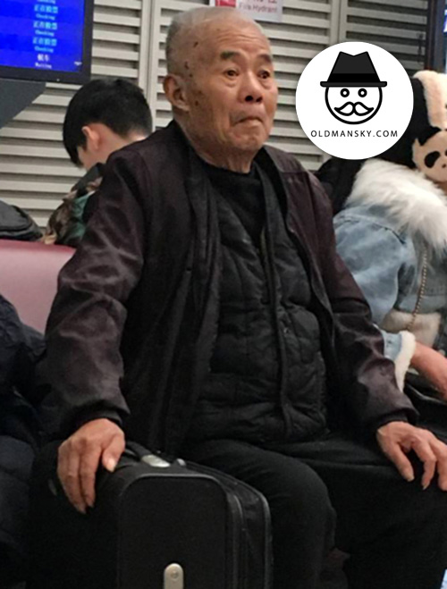 Old man wore black clothes sat on the bench in the railway station