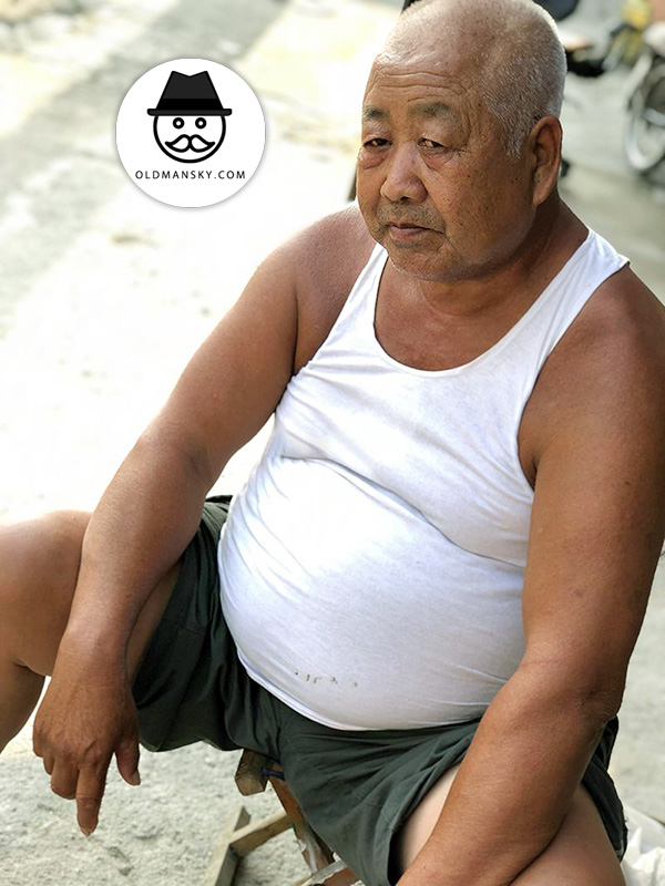 Fat old man wore white vest and sat by the roadside