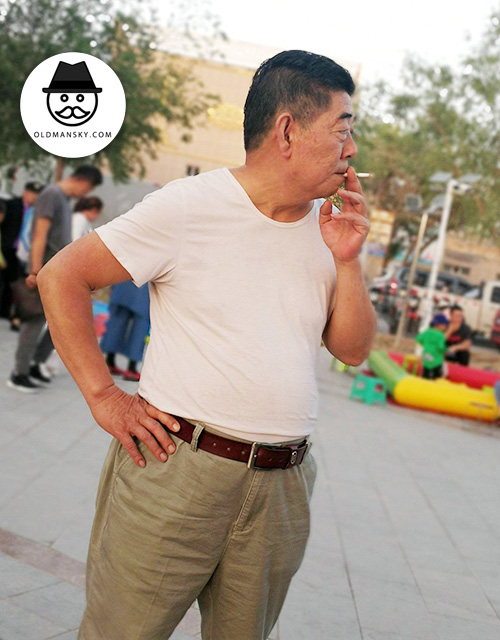 Old daddy wore white T-shirt and smoke in the children’s playground
