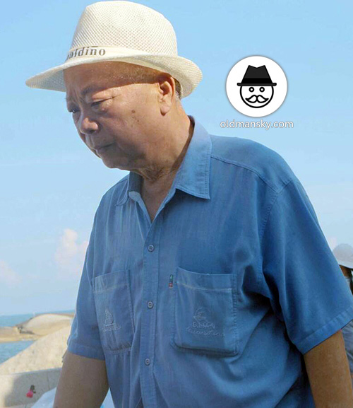 Old daddy wore blue shirt and a hat stood at the sea