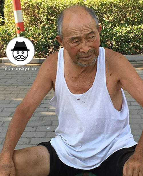 Old man wore white vest undershirt and black pants rest in the park