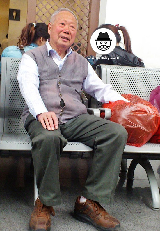 Silver hair old man wore green pants and gray vest sat in the railway station