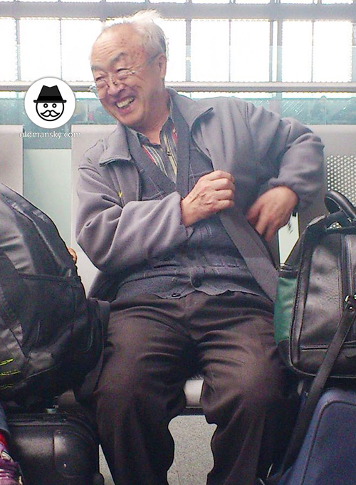 White hair glasses old man wore gray coat sat on the railway station chair