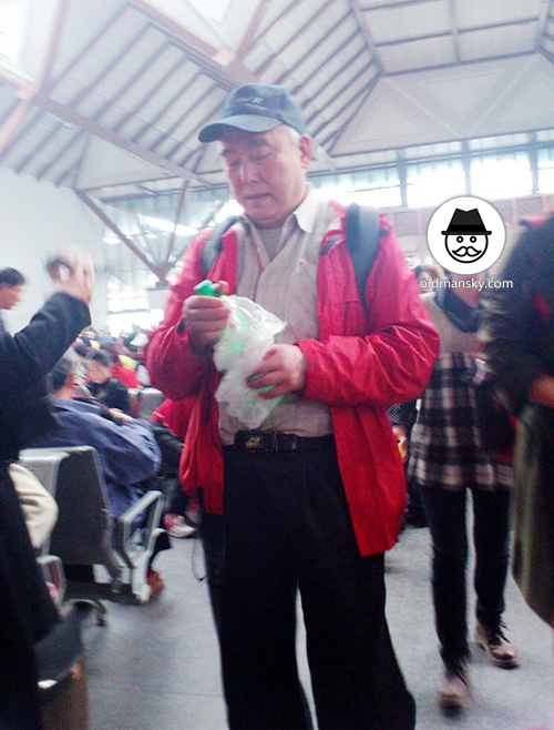 Old man wore a cap and red coat in the railway station