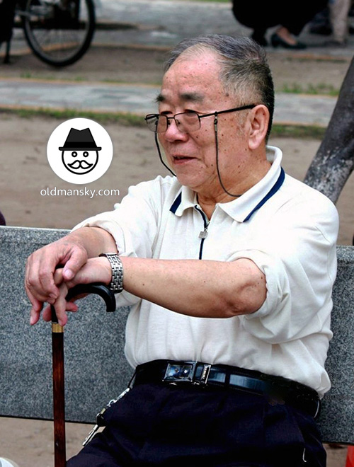 Old man wore white polo shirt rest on bench in the park