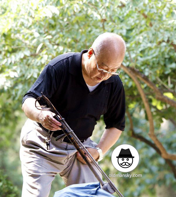 Glasses old man was playing erhu in the park