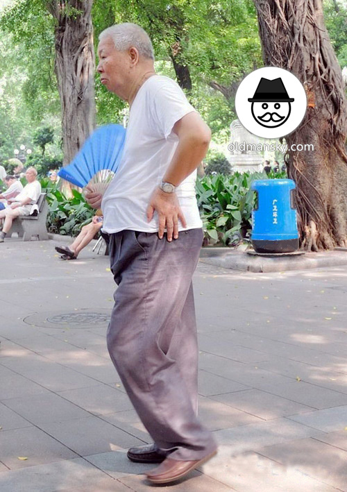 Old man wore white undershirt and gray trousers in the park