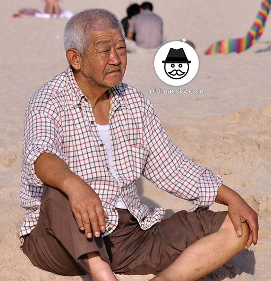 White hair old man wore plaid shirt sat on the beach