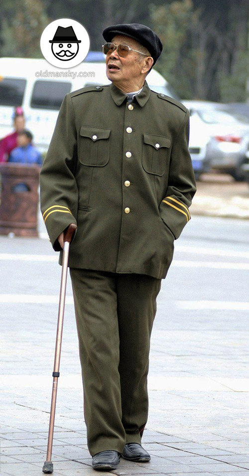 Thin old man walked on the road in military uniform with a crutch_02