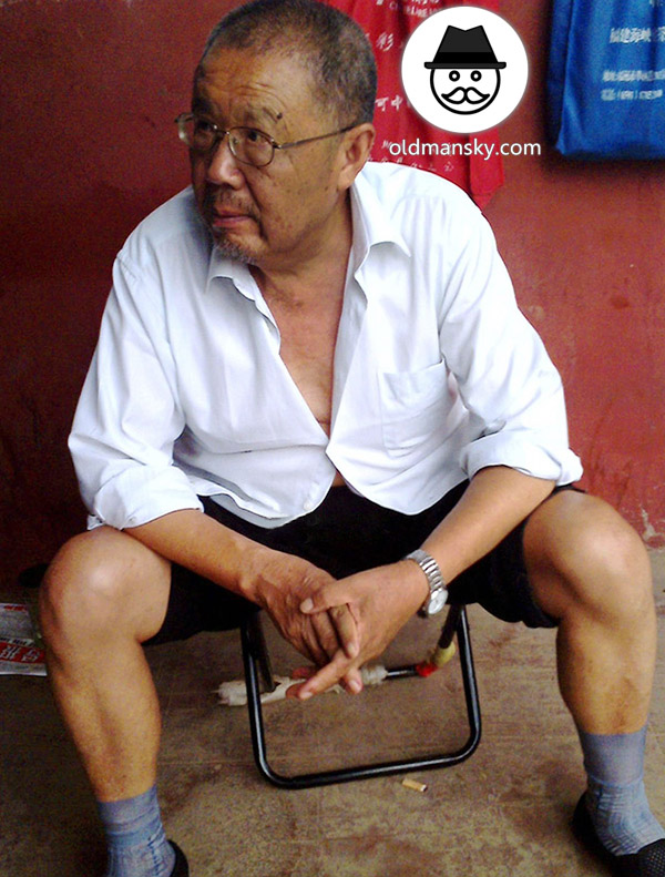 Glasses old daddy wore white shirt and black trousers sat by the roadside_02