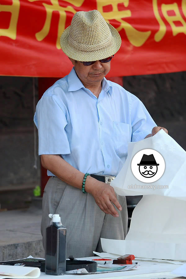 Old daddy wore blue shirt and a hat was writing in the street_04