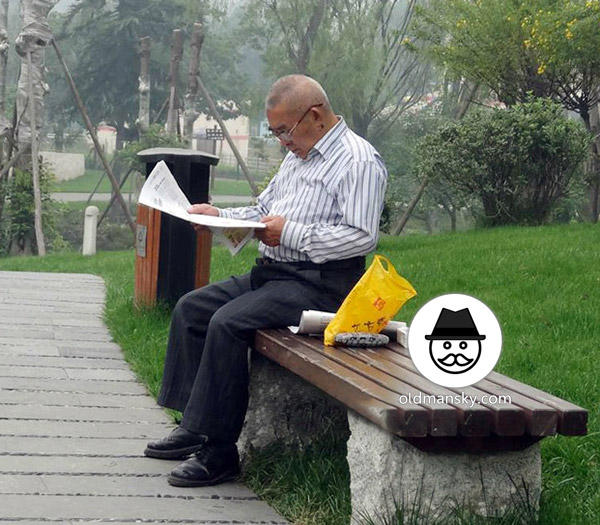 Glasses old daddy wore strip shirt was reading newspaper on the bench_03