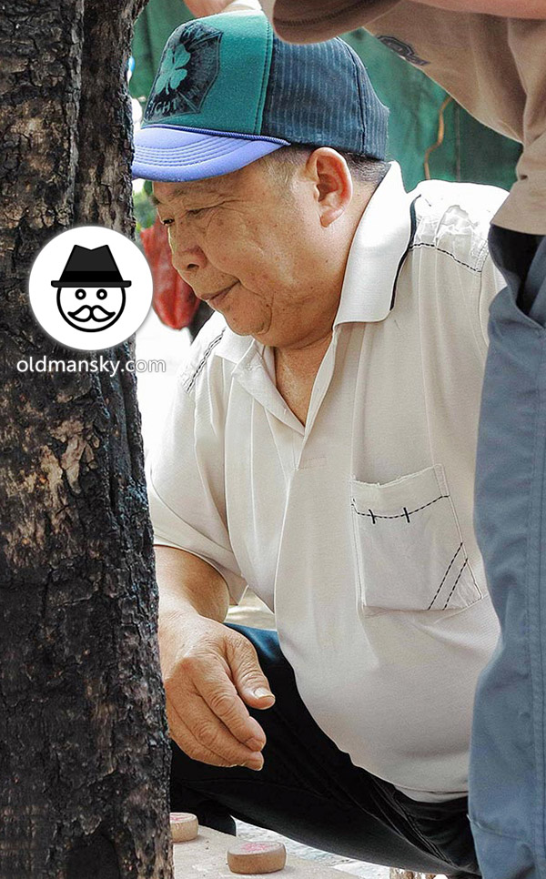 Old daddy wore white polo shirt was playing Chinese chess in the park_02