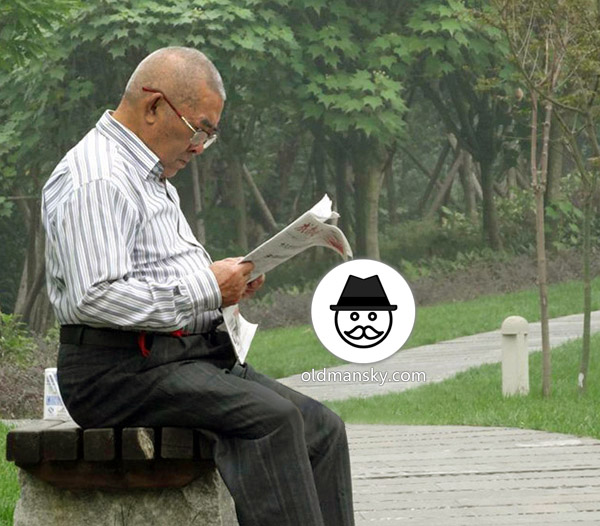 Glasses old daddy wore strip shirt was reading newspaper on the bench
