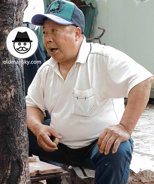 Old daddy wore white polo shirt was playing Chinese chess in the park