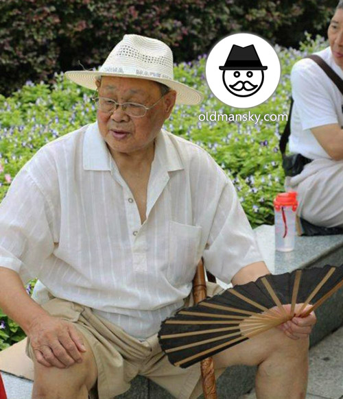 Glasses old man wore a white hat and took a fan rest in the park