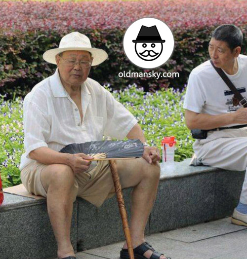 Glasses old man wore a white hat and took a fan rest in the park_03
