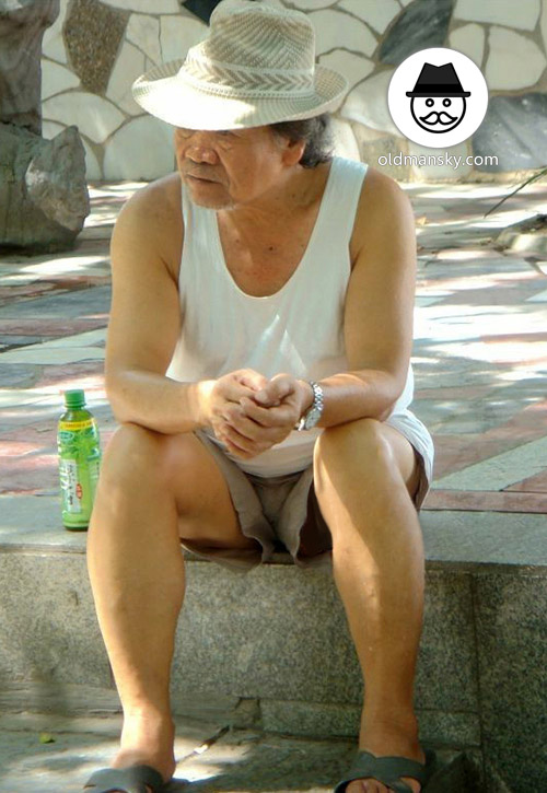 Old man wore white vest undershirt and middle pants sat in the park