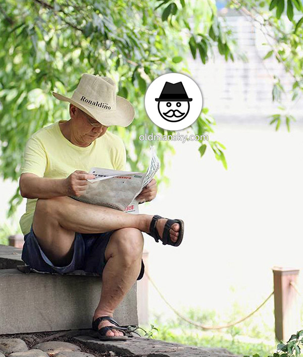 Glasses old daddy wore a yellow t-shirt was reading newspaper by the lake_03