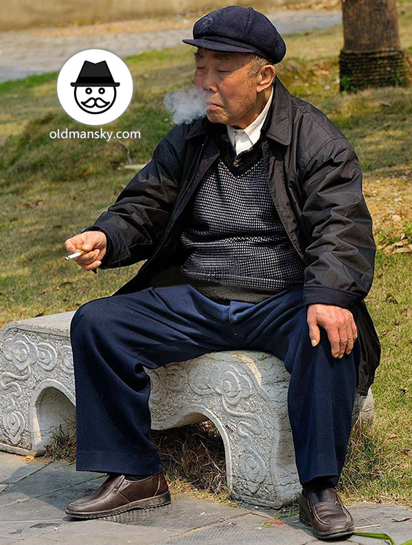 Old man wore a black hat was smoking sat on a stone bench in the park_05