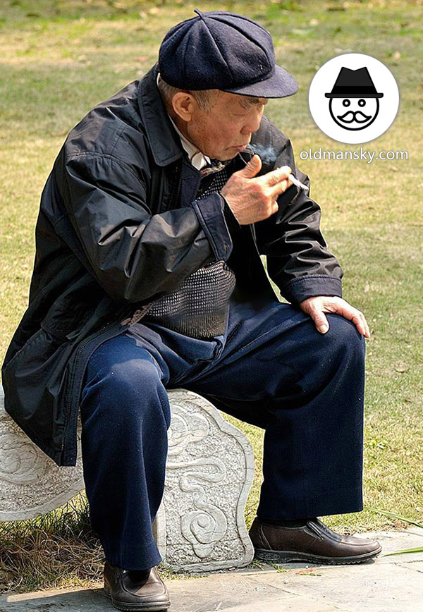 Old man wore a black hat was smoking sat on a stone bench in the park_06