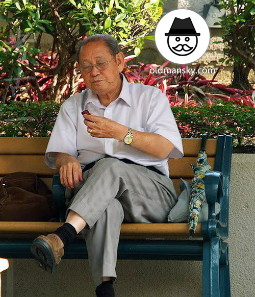 Glasses old man wore white short sleeve shirt sat on the bench in the park_03