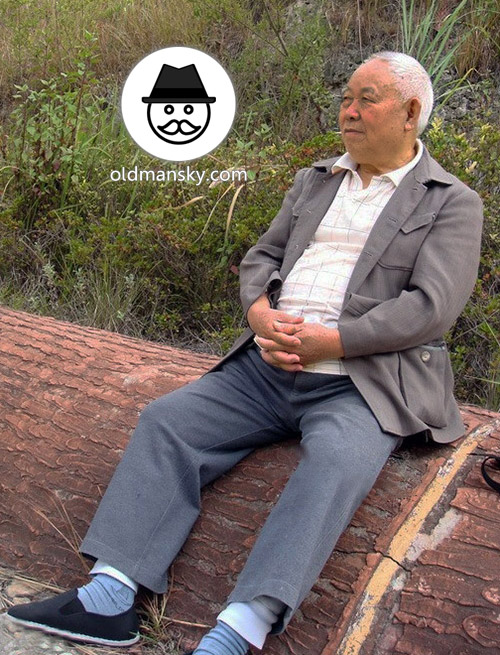 Tourist white hair old man wore gray clothes rest on the stone bench