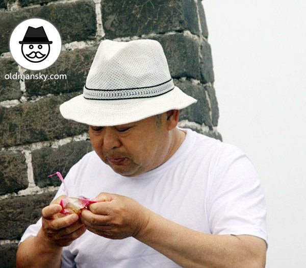 Fat old daddy wore a white hat and white T-shirt was eating on the Great Wall