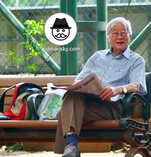 White hair glasses old man was reading newspapers on the park bench