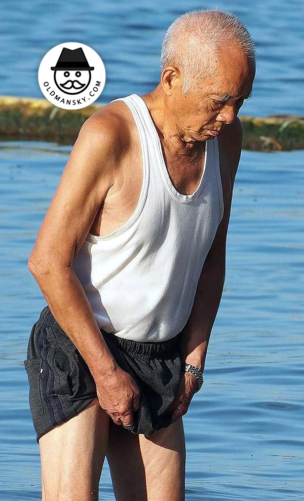Old man wore a white vest undershirt and a black middle pants at the sea