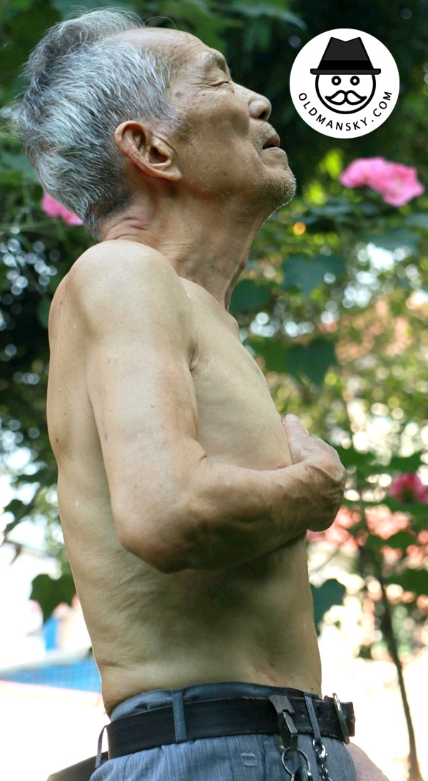Thin silver hair old man wore a blue trousers was doing exercise in the park