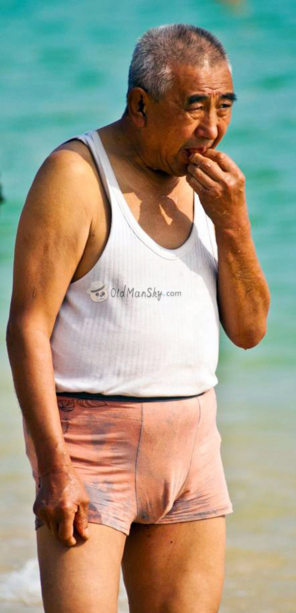 Old man wore white vest undershirt stood on the beach