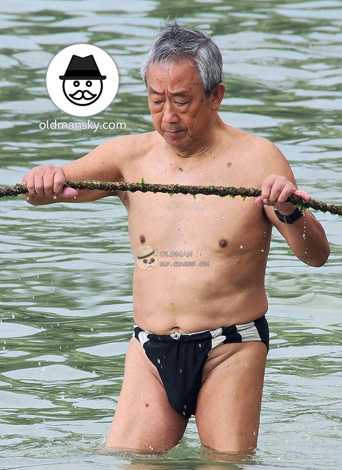 Swimming old man wore a black underwear stood in the water