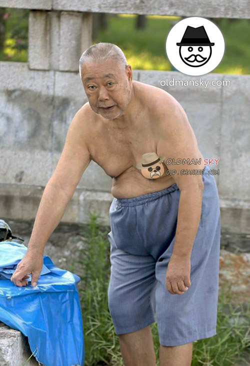 Swimming fat old man was changing his gray middle pants by the river