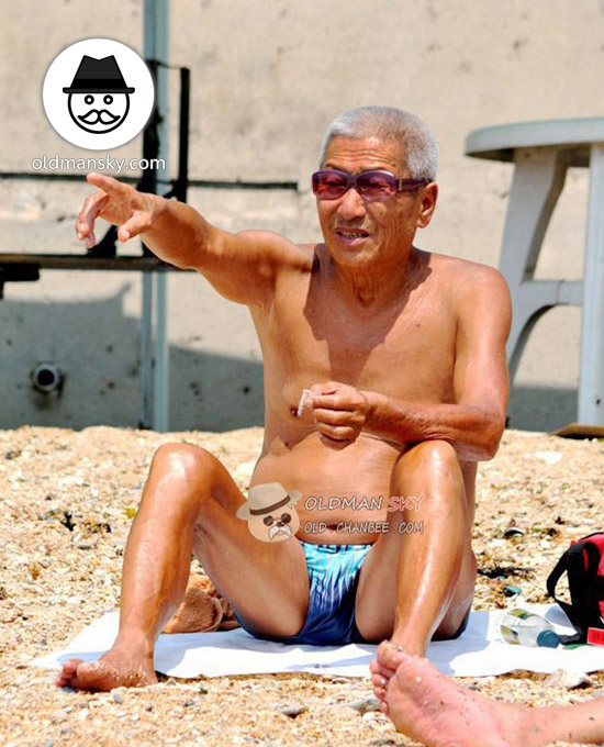 White hair swimming old man wore a sunglasses sat on the beach