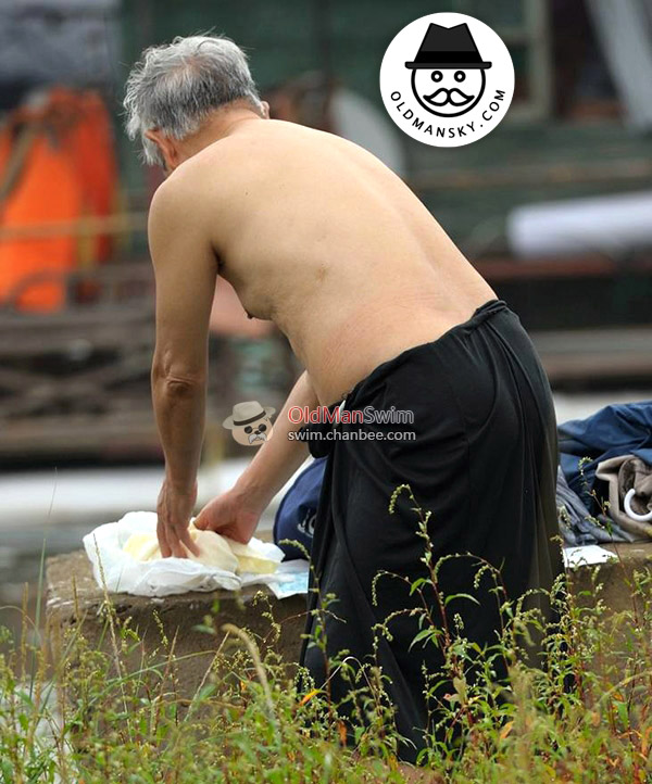 Swimming white hair old man put on his blue boxer underwear by the river