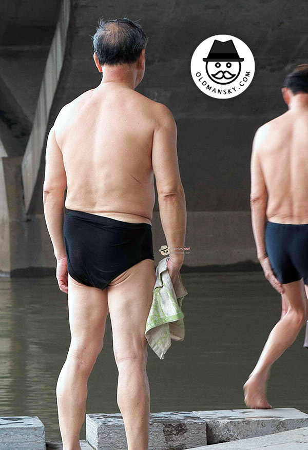 Swimming old daddy wore a black underwear stood by the river
